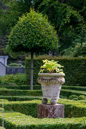 An ornate stone pot in a well trimmed green garden