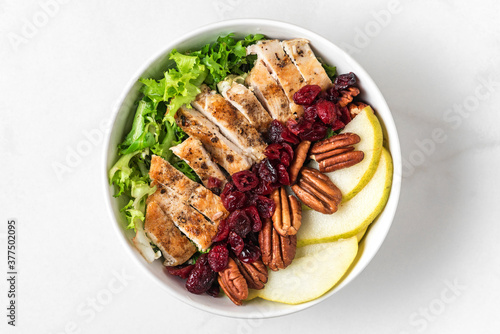 healthy chicken lunch bowl salad. Chicken breast, pear, pecan nuts and dried berries autumn salad. Top view