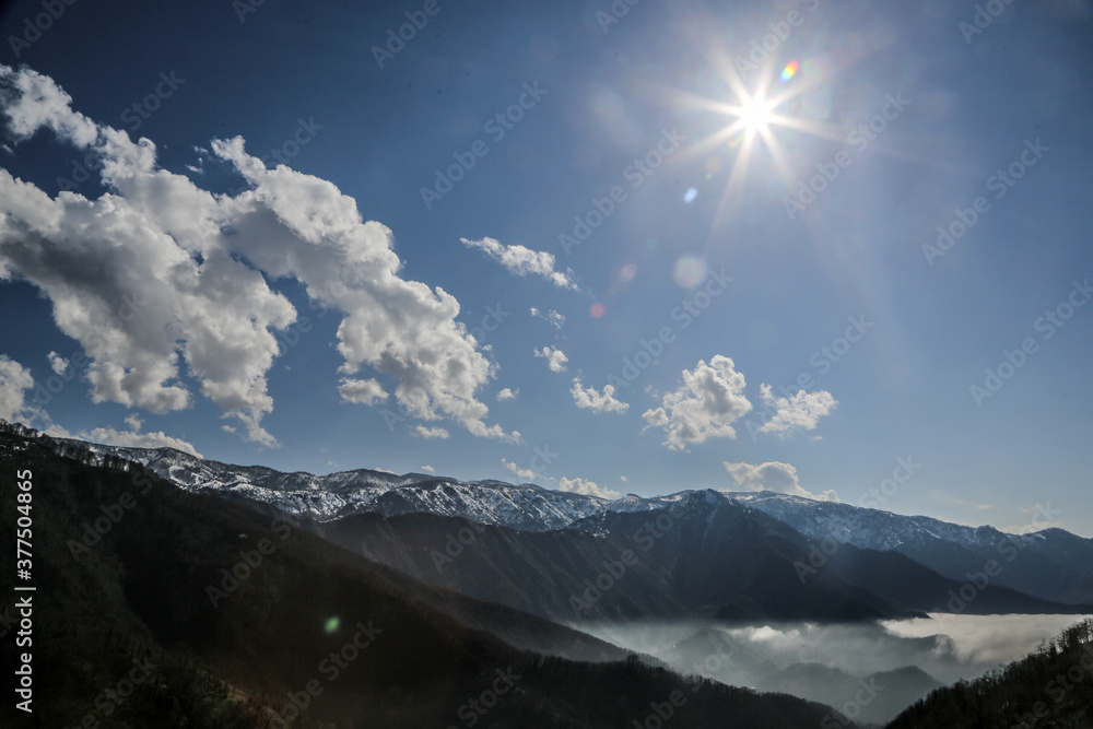 Mountain range seen from above with sunlight and clouds
