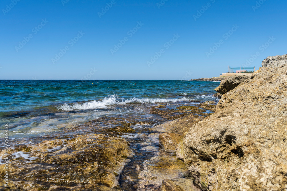 Rocky shore of Posto Rosso, Salento, Puglia, Southern Italy, in a sunny summer day, with bright colors, clear water and blue sky. 