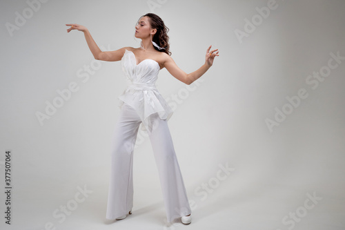 Fototapeta Naklejka Na Ścianę i Meble -  A young brunette woman in a stylish and elegant pantsuit. Wedding suit with trousers, modern style.