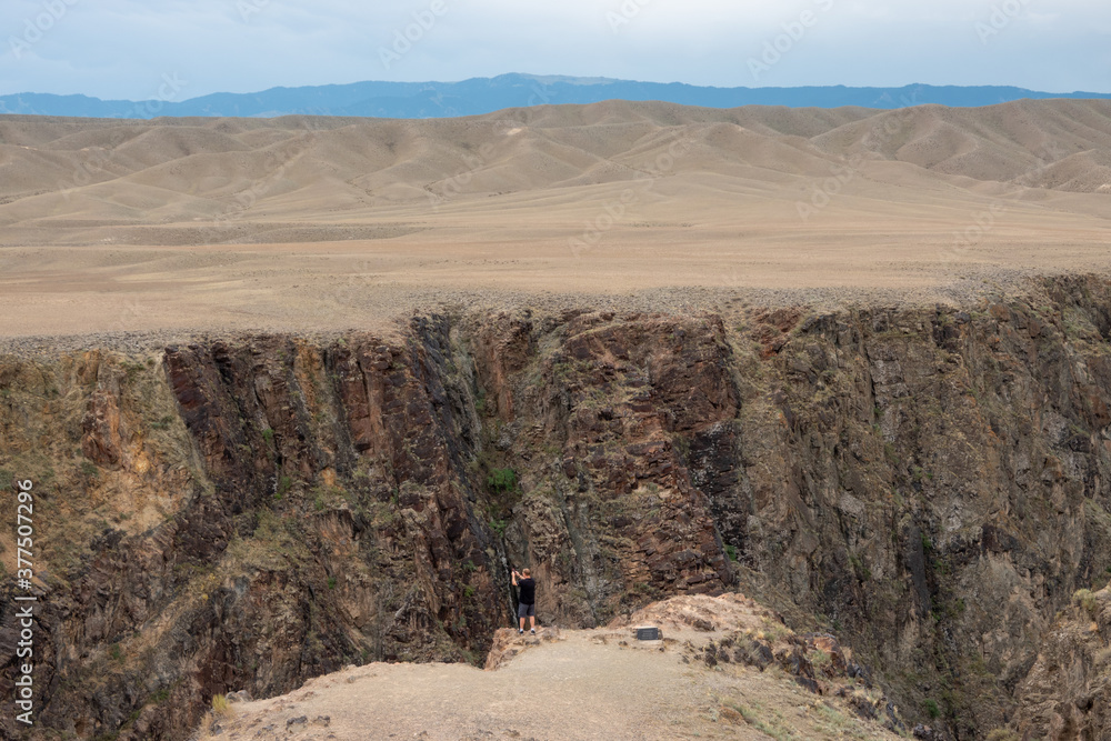 a man stands on the edge of the canyon and takes a photo