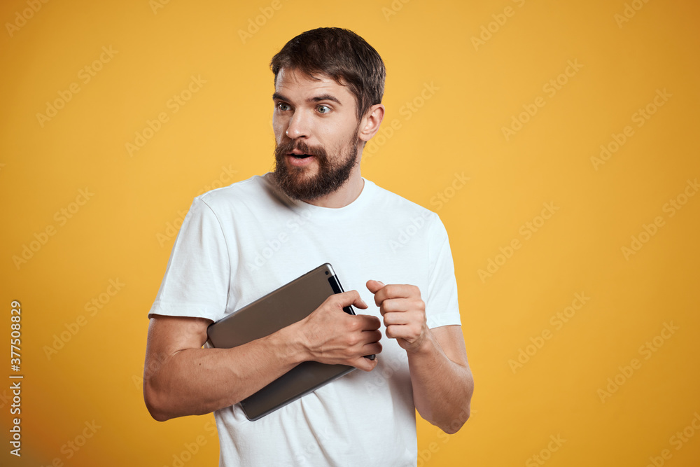 Man with a tablet on a yellow background in a white t-shirt new technologies businessman touch screen touchpad Man with a tablet on a yellow background in a white t-shirt new technologies businessman touch screen touchpad