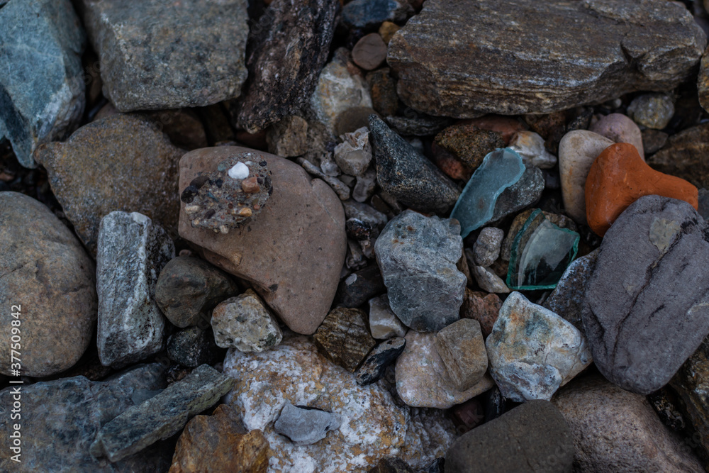 large and small rough broken colorful texture stones with glass on shore of lake, sea large and small rough broken colorful texture stones with glass on shore of lake, sea
