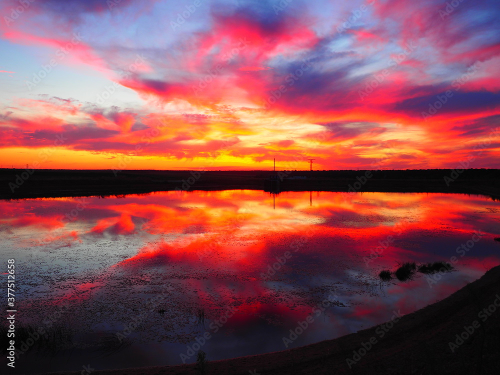 Red and orange sky reflected in a lake at sunset