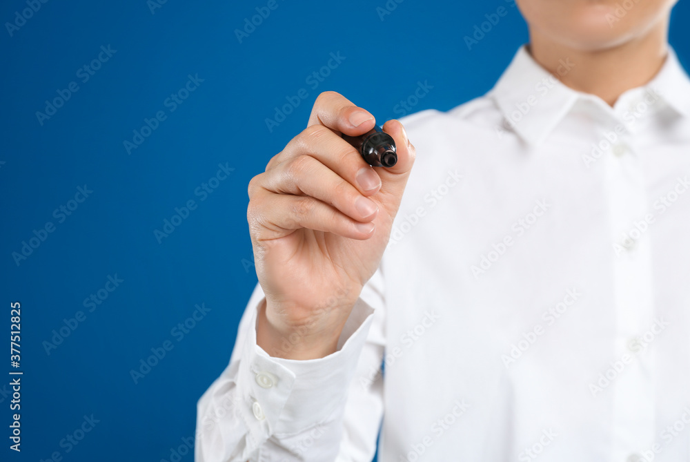 Woman with marker against blue background, focus on hand Woman with marker against blue background, focus on hand