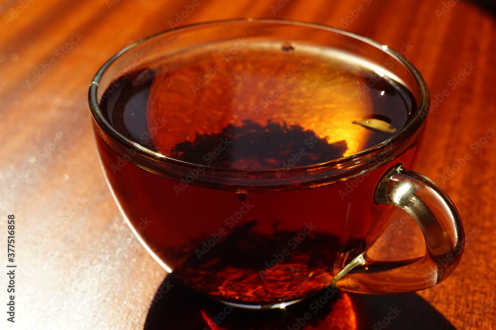 Transparent cup with black tea on the brown wooden table. Transparent cup with black tea on the brown wooden table.