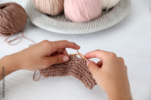 Young woman knitting with needles indoors, closeup. Engaging in hobby