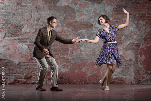 a young couple dancing swing against an old brick wall