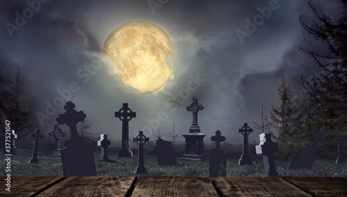 Fotografie Wooden surface and moonlit graveyard with old creepy headstones on Halloween
