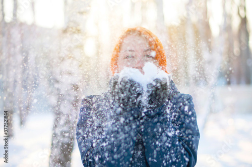 Cute girl blows on snowflakes in her hands. Winter holidays and joyful concept.