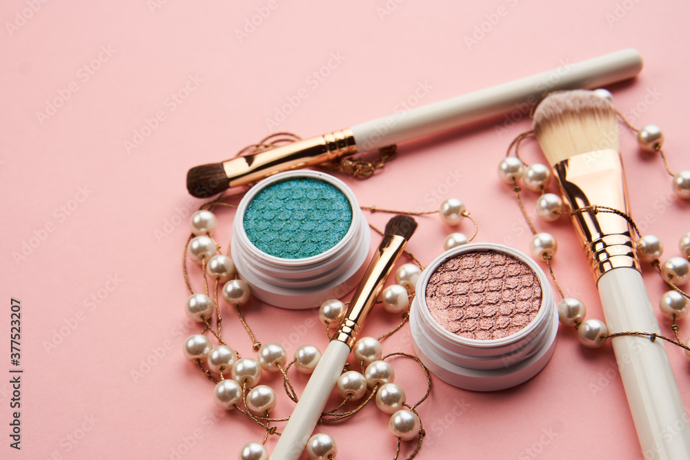 Fototapeta premium eyeshadow accessories beads makeup brushes collection professional cosmetics on pink background