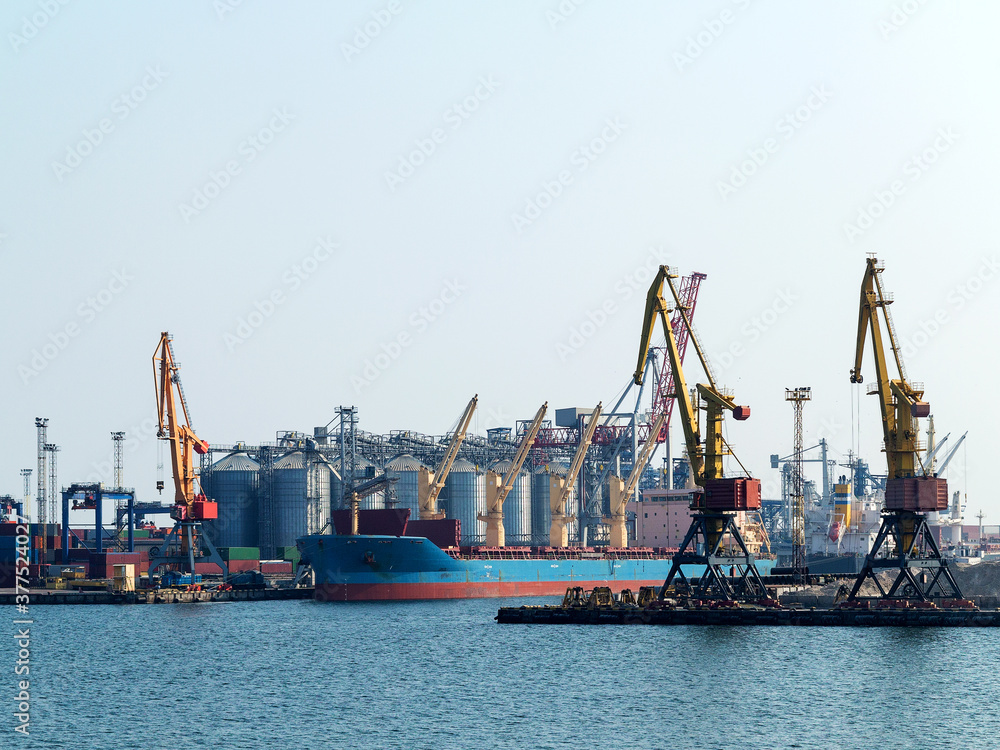Large cranes for loading goods on large marine cargo ships at the container terminal in the port of Odessa sea port on a foggy day