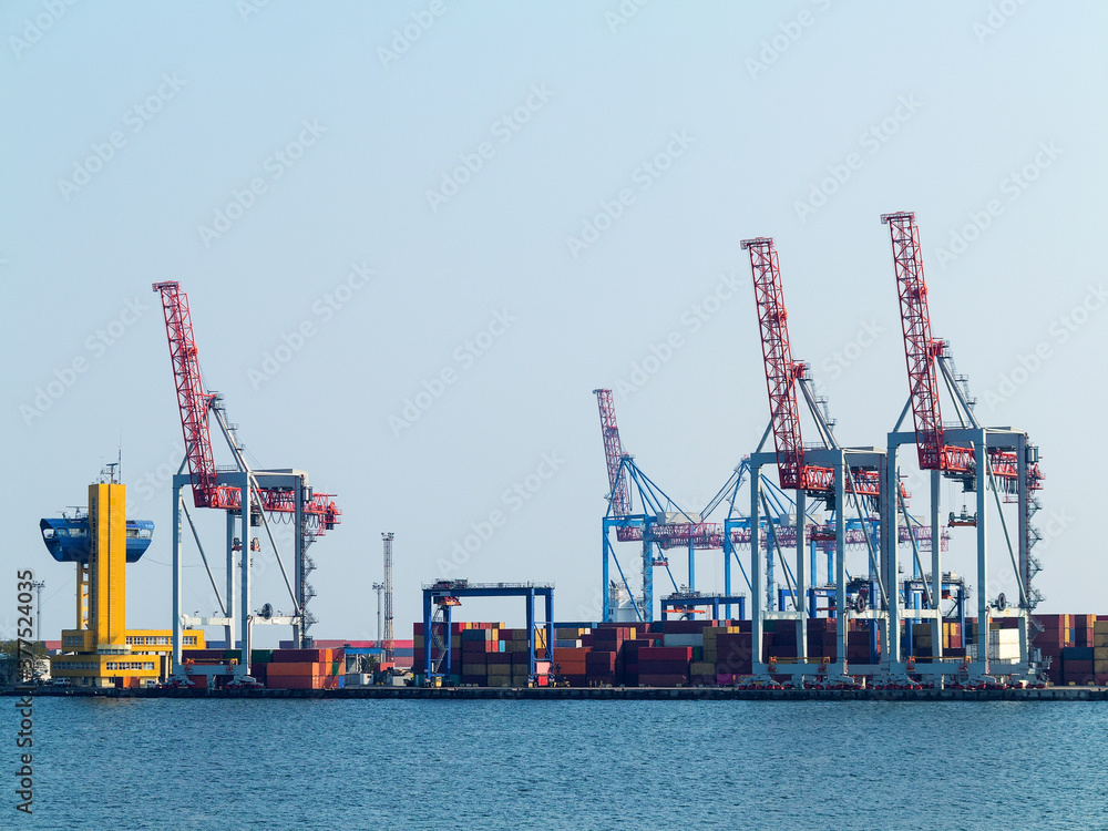 Fototapeta premium Large cranes for loading goods on large marine cargo ships at the container terminal in the port of Odessa sea port on a foggy day