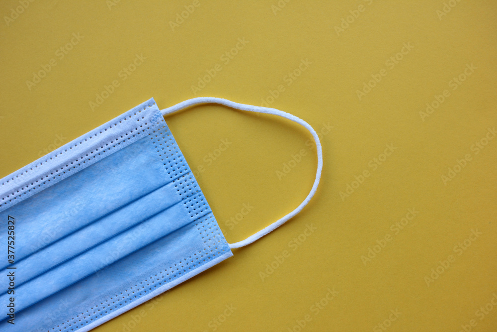 Disposable medical face mask on a yellow background with copy space. Pandemic protective face cover. Disposable medical face mask on a yellow background with copy space. Pandemic protective face cover.