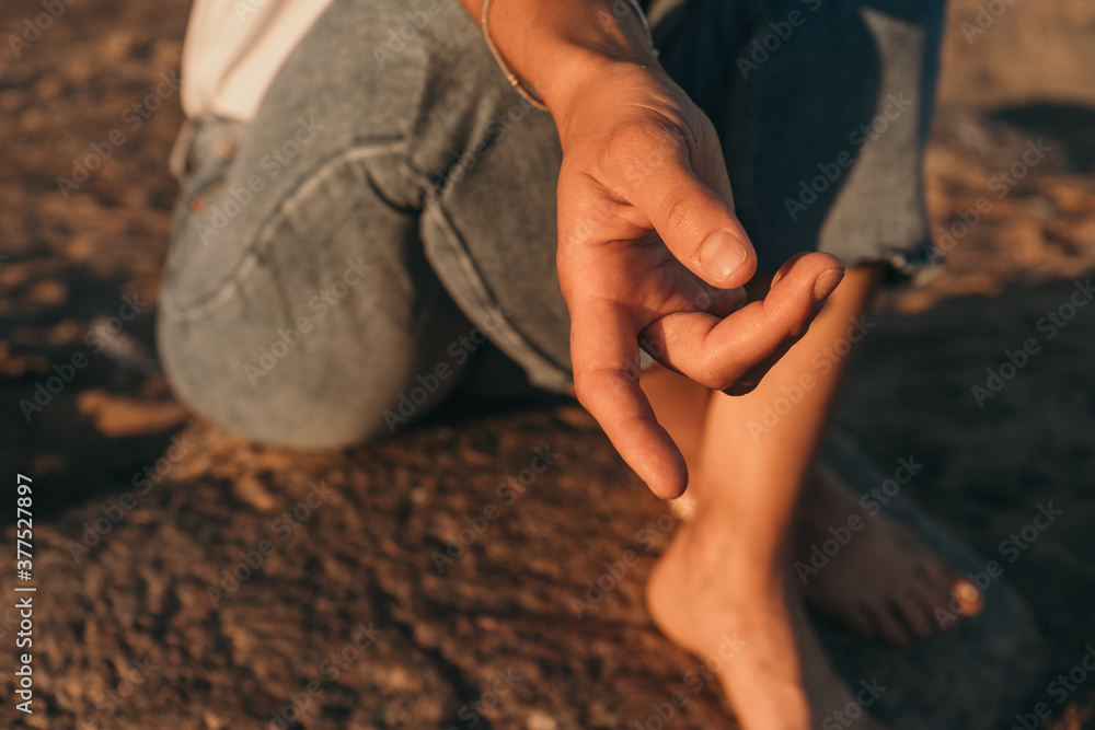 Female hand close-up. A girl warms her hands at sunset by the sea.