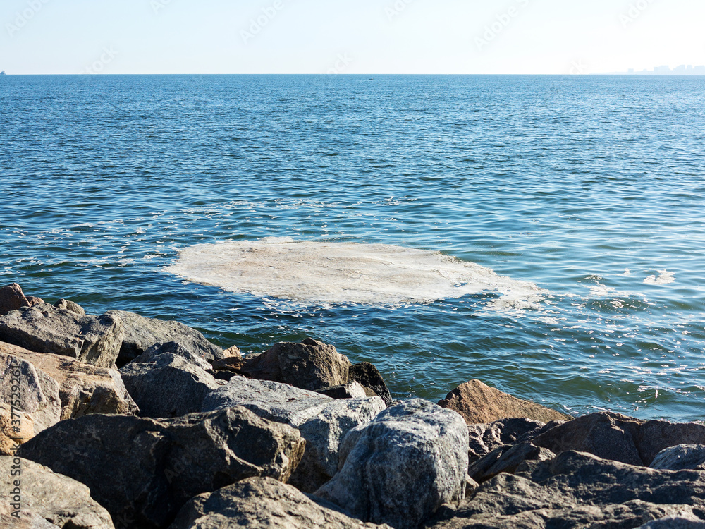 Full frame take of some extremely polluted waters. Dirty sea water. Dirt on water. Dirty oil spots on surface of sea water are polluted as result of sewage runoff. Mud ripples. Ecological problem. 