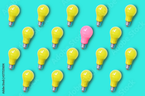 Pattern of yellow lightbulb on green turquoise background with only one lightbulb in pink color , differentiation and uniqueness concept