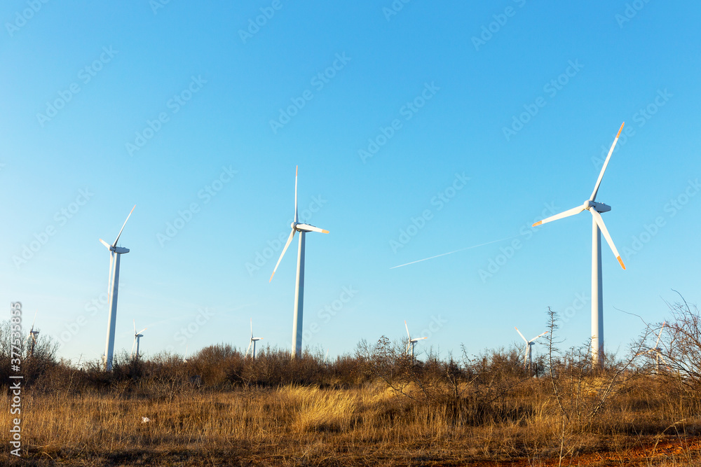 Wind Turbines at Dusk. Landscape sunset with windmills. Renewal source of electricity. Wind turbines field new technology for clean energy on mountain, sunset view with colorful twilight on sky Wind Turbines at Dusk. Landscape sunset with windmills. Renewal source of electricity. Wind turbines field new technology for clean energy on mountain, sunset view with colorful twilight on sky