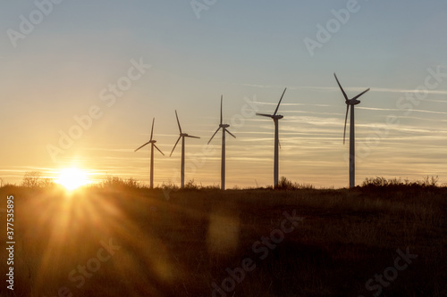 Wind Turbines at Dusk. Landscape sunset with windmills. Renewal source of electricity. Wind turbines field new technology for clean energy on mountain  sunset view with colorful twilight on sky