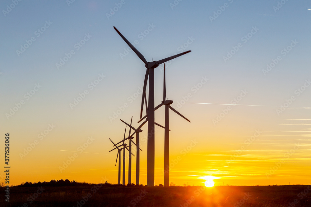 Fototapeta premium Wind Turbines at Dusk. Landscape sunset with windmills. Renewal source of electricity. Wind turbines field new technology for clean energy on mountain, sunset view with colorful twilight on sky
