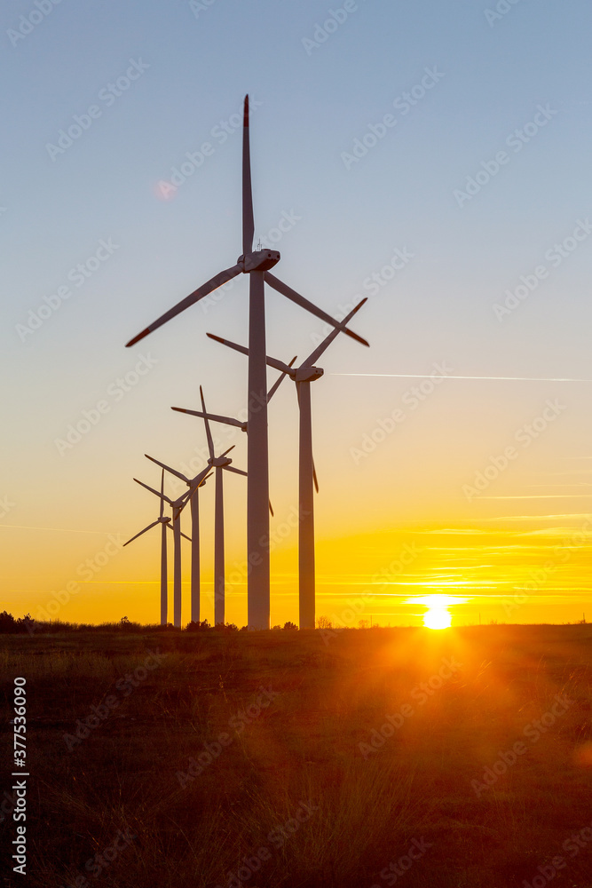 Obraz premium Wind Turbines at Dusk. Landscape sunset with windmills. Renewal source of electricity. Wind turbines field new technology for clean energy on mountain, sunset view with colorful twilight on sky