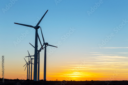 Wind Turbines at Dusk. Landscape sunset with windmills. Renewal source of electricity. Wind turbines field new technology for clean energy on mountain, sunset view with colorful twilight on sky