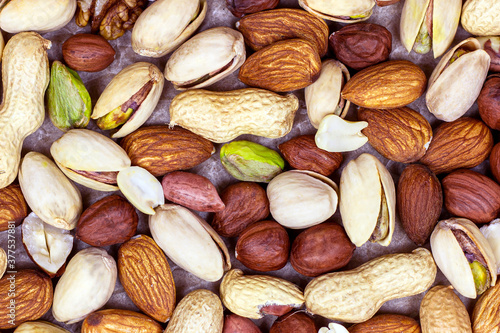 Top view of different nuts: almonds, pistachios, peanuts, hazelnuts texture on light background.