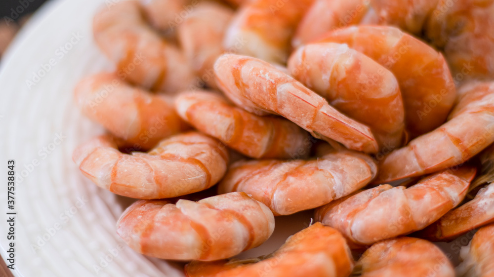Tiger prawns on a large white plate, blurred background. Seafood.
