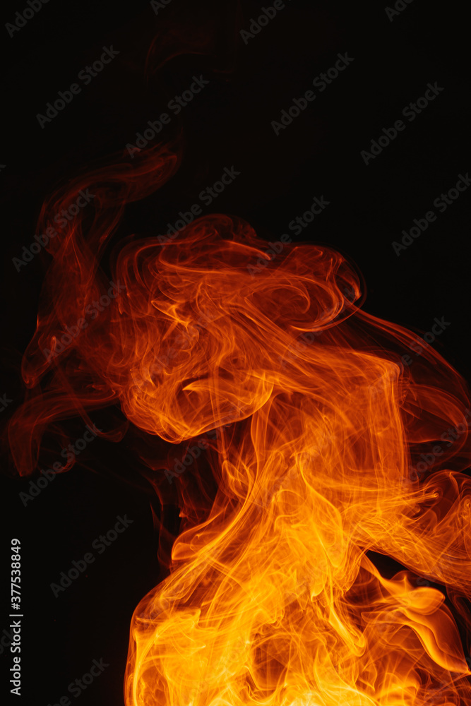 Fototapeta premium Orange smoke on a dark background. Intricate swirls of colored smoke. An abstract imitation of night flames.