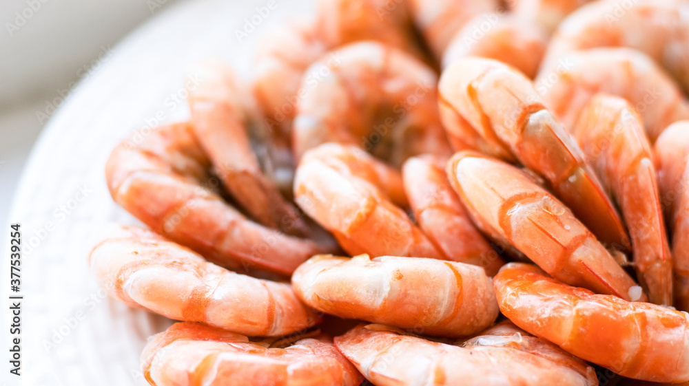 Tiger prawns on a large white plate, blurred background. Seafood. Tiger prawns on a large white plate, blurred background. Seafood.