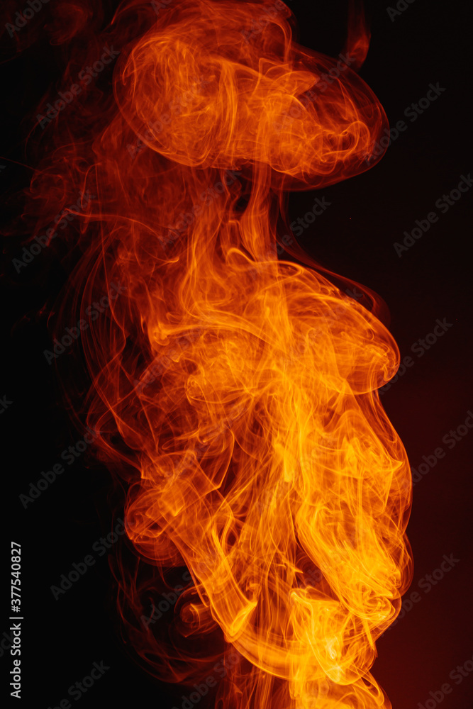 Orange smoke on a dark background. Intricate swirls of colored smoke. An abstract imitation of night flames. Orange smoke on a dark background. Intricate swirls of colored smoke. An abstract imitation of night flames.
