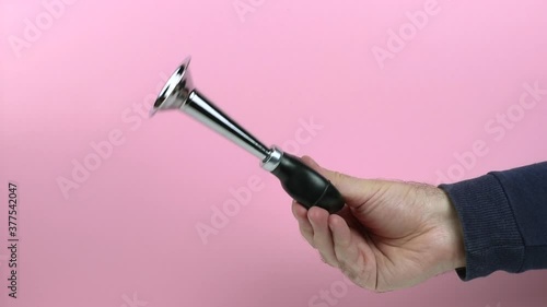 caucasian hand of a man with a vintage metal klaxon against a pink background close-up
 photo