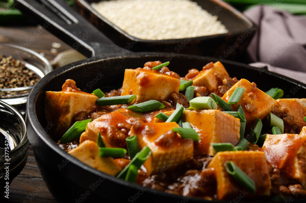 Mapo tofu dish with pork chives soy sauce garlic and spices closeup in cast iron skillet Mapo tofu dish with pork chives soy sauce garlic and spices closeup in cast iron skillet