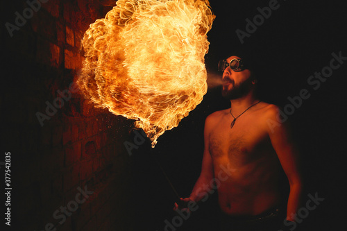 Male fakir blowing out fire in an abandoned building at night. Fire performer blowing out fire close-up.