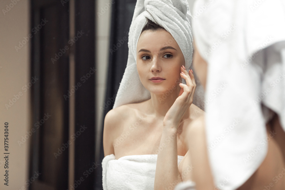 Young woman in bathroom behind mirror Young woman in bathroom behind mirror