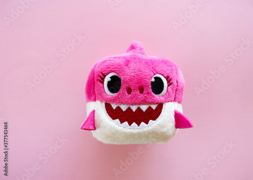 Adorable pink baby shark soft toy on pink background. Sweet childhood. Free copy space. Top view