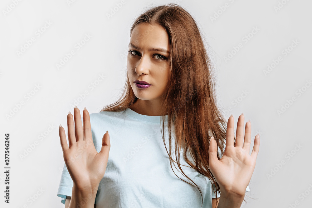 Stop. Enough. Young beautiful girl stretches out her hand to the camera to stop the effect. Woman with fashion makeup with purple lips on an isolated gray background. Bad events, despair and threat. Stop. Enough. Young beautiful girl stretches out her hand to the camera to stop the effect. Woman with fashion makeup with purple lips on an isolated gray background. Bad events, despair and threat.