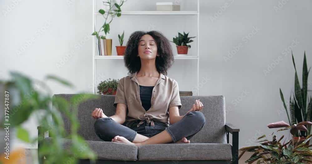 Calm relaxed African woman sitting at home on sofa with closed eyes ...
