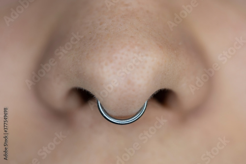 Nose piercing septum. Beautiful piercing jewelry. Macro shot. Selective focus.