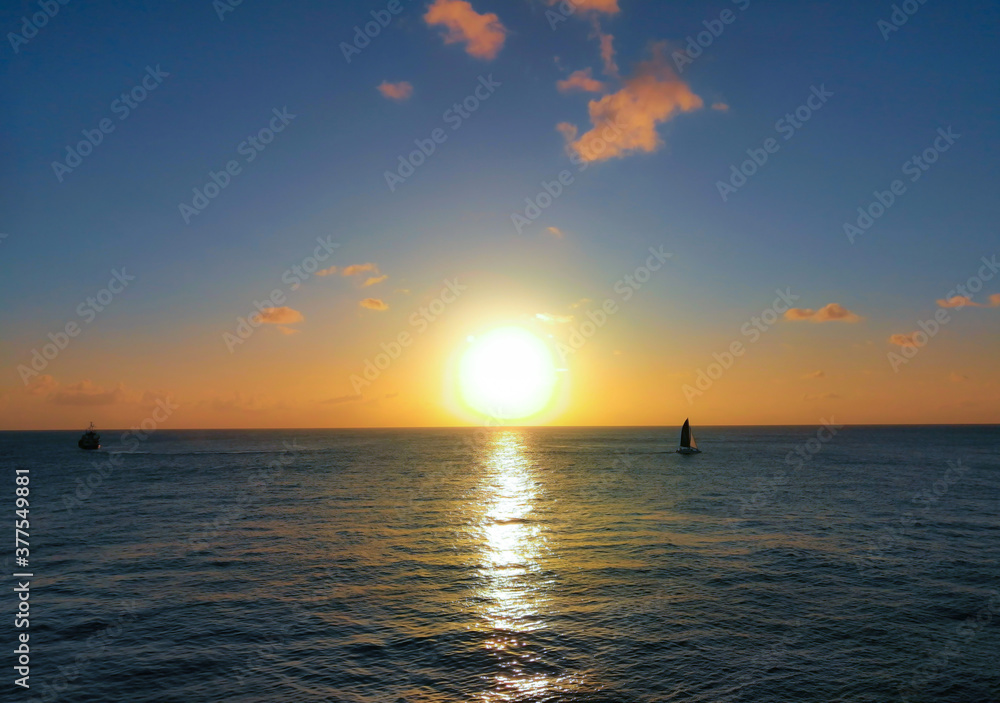 Beautiful sunset with large yellow sun above the sea surface and silhouettes of two small boats