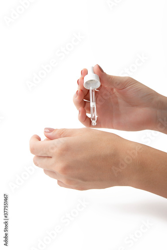 Hand holding luxury serum dropper. Vitamins collagen skin treatment. Close up