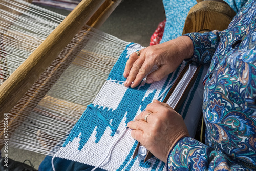 Woman hand weaving on manual loom. Fabric handmade. The process of fabric weaving in vintage weaver machine.