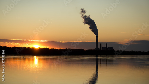 Nature and Industry. Silhouette of an industrial smoke stack and smoke alongside a beautiful sunset on the Mississippi River on the Great River Road in the Alton and Godfrey Illinois area. Copy space. photo