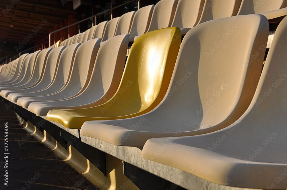 Fototapeta premium Tribune seat with one different Color,Tribune in Hockenheim , Side view, one new yellow Seat, old rowof seat