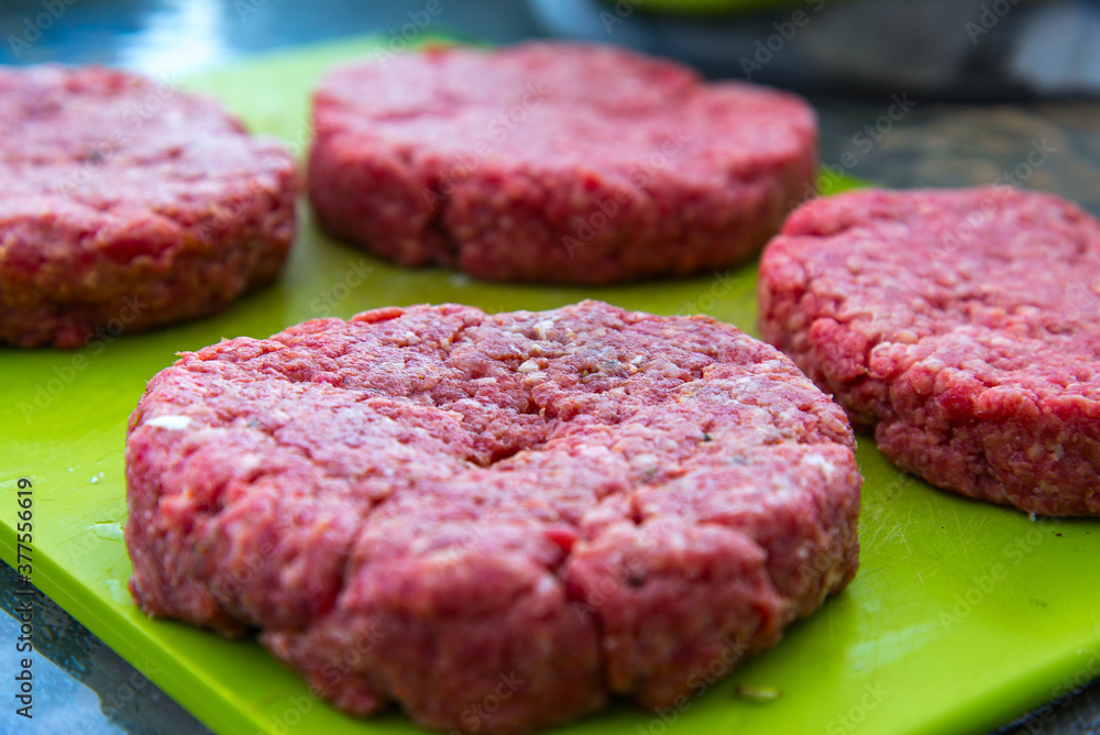 Raw beef burgers close up on a chopping board Raw beef burgers close up on a chopping board