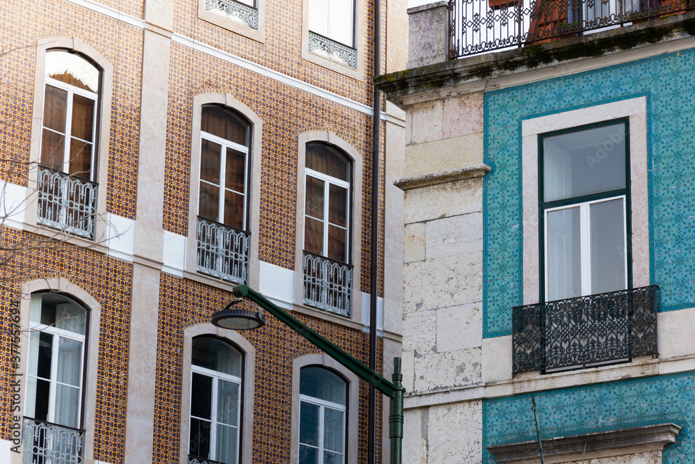 Fototapeta premium Angle perspective of brown and blue tile buildings in Lisbon. Traditional facades with street light in the middle in Portugal residential area