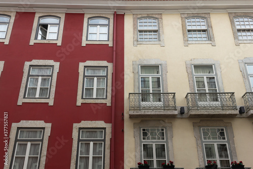 Red and white building front facade with windows and balconies in Lisbon, Portugal. Real estate, urban city, residential area concepts
