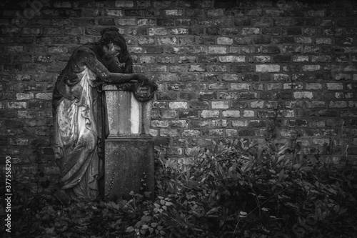 Vintage, retro photo of a statue in the Old Southern Cemetery (Alter Südfriedhof) of Munich. Grainy, noisy, artistic monochrome image. Halloween, all saints concept
