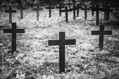 Vintage, retro black and white photo of old graves and crosses in a cemetery. Grainy, noisy, artistic monochrome image. Halloween, all saints concept